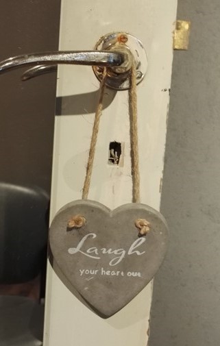 Sydän-koriste ovenkahvassa, teksti ”Laugh your heart out”